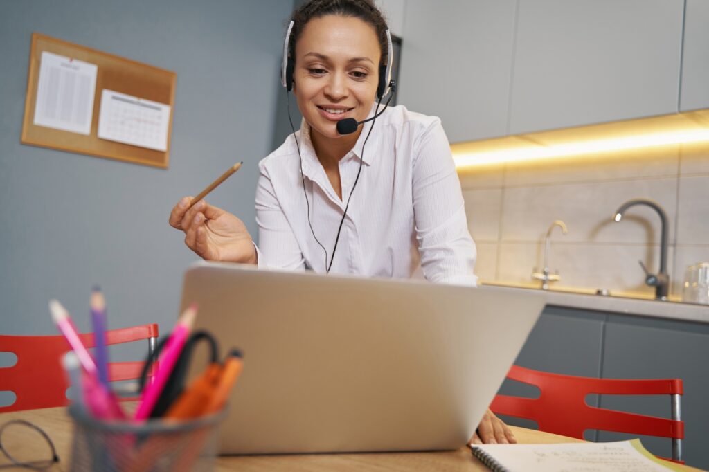 Positive online teacher giving explanations to students before laptop